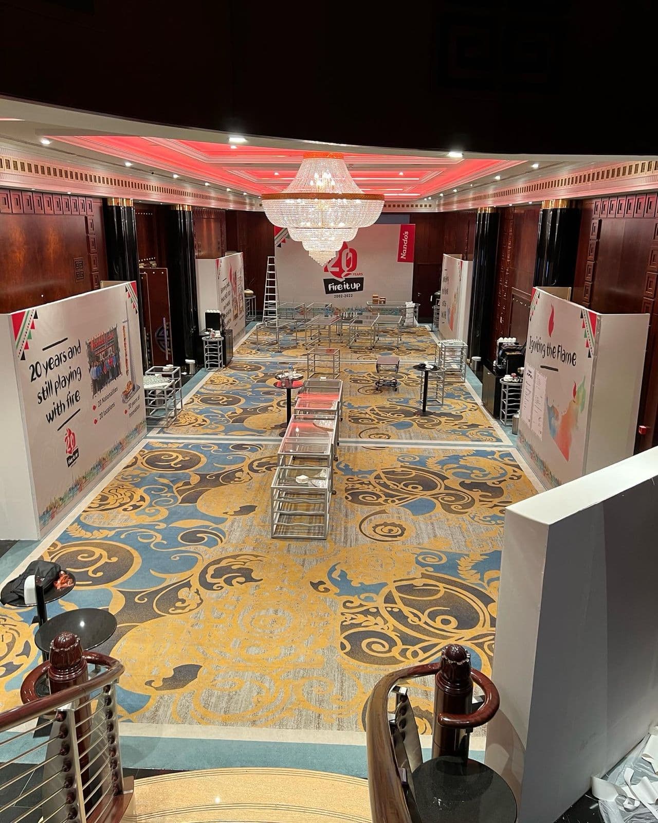 Nando's 20th anniversary ballroom setup with chandelier and 'Fire it Up' branded panels