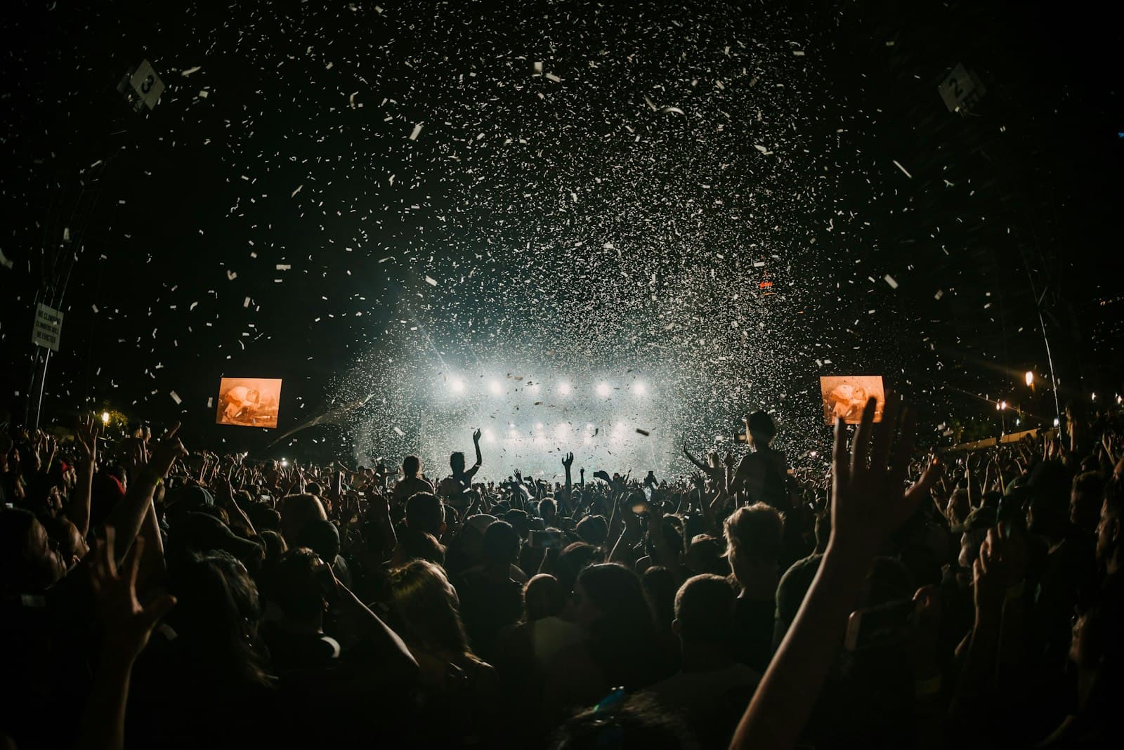 Crowd at a live event under a confetti blast and stage lights