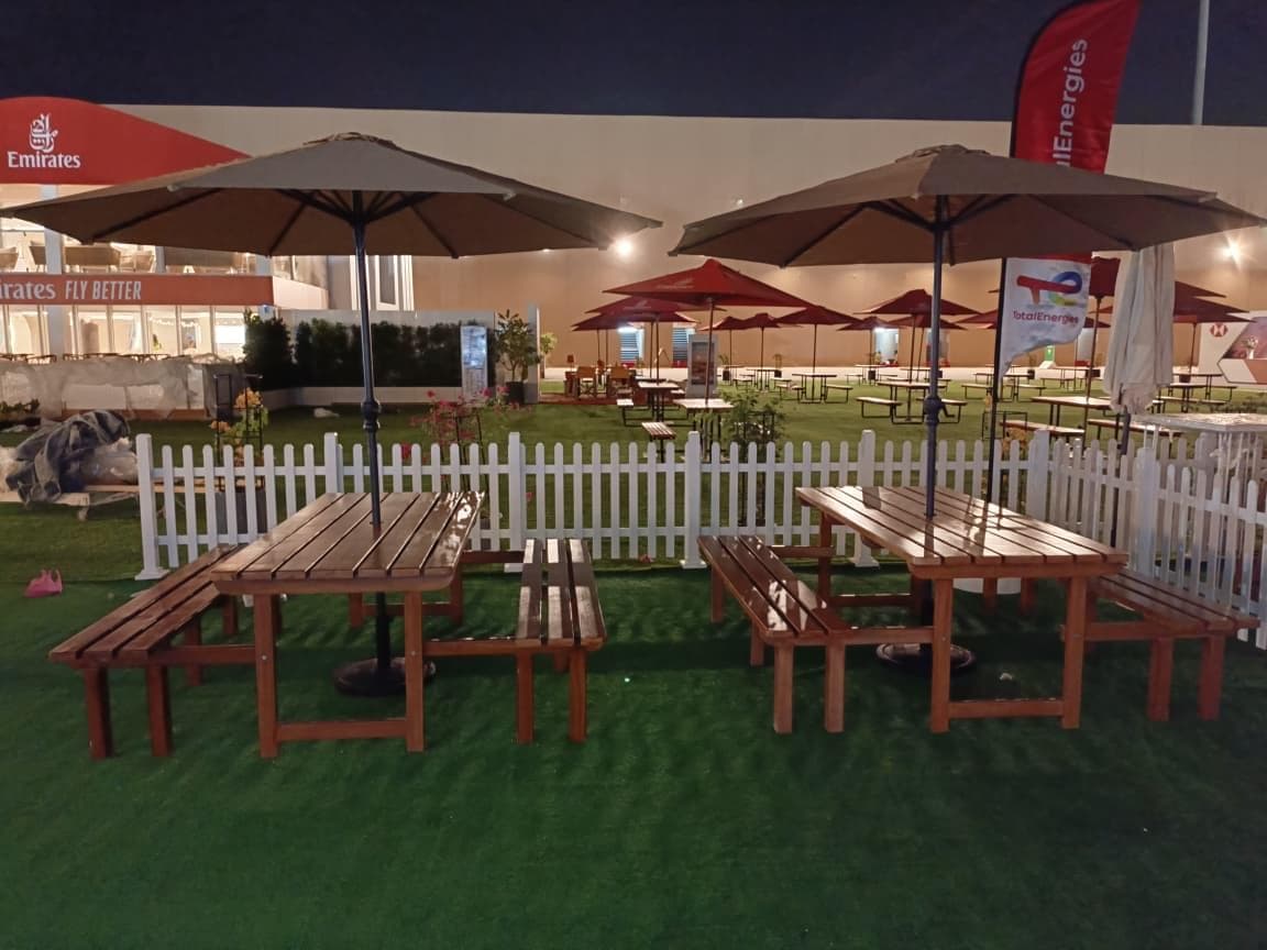 TotalEnergies hospitality seating with picnic tables, parasols and branded flags at night