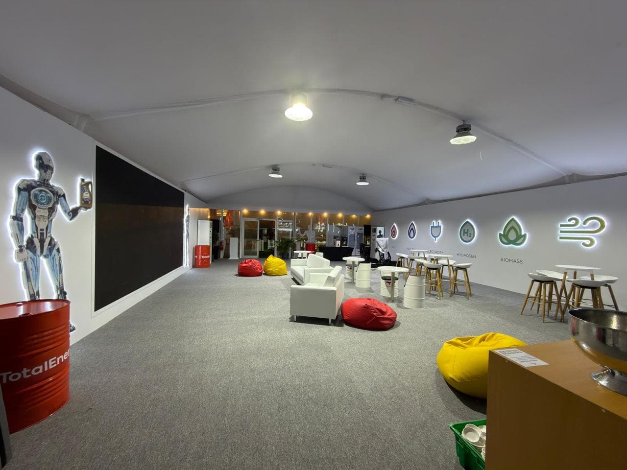 TotalEnergies interior lounge with bean bags, sofas, branded oil drum and a backlit energy-transition wall
